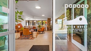 A hotel lobby with a reception area, seating, and a view of the outdoor garden.
