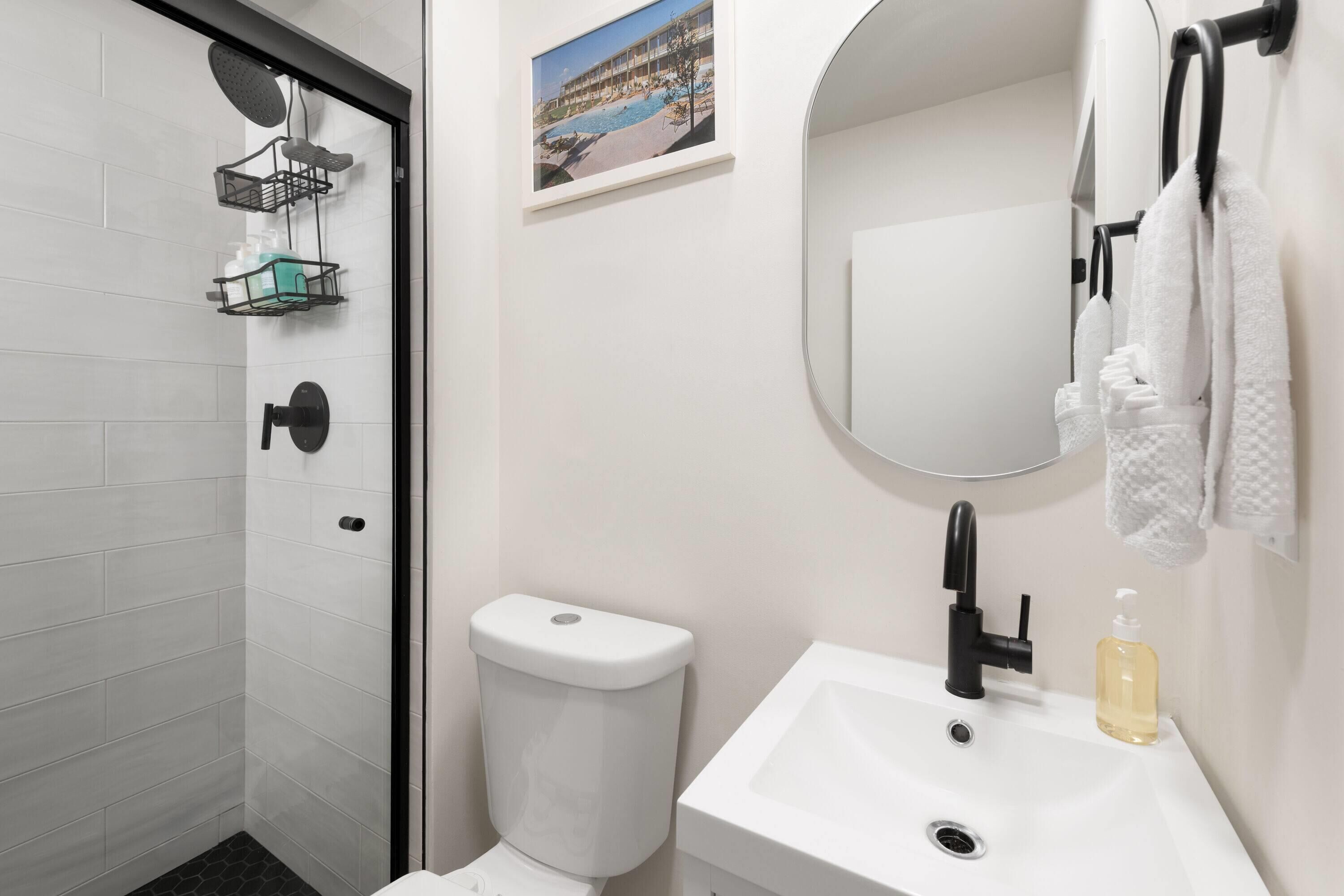 Une salle de bain moderne équipée d’une douche, de toilettes, d’un lavabo et d’un tableau encadré au mur.