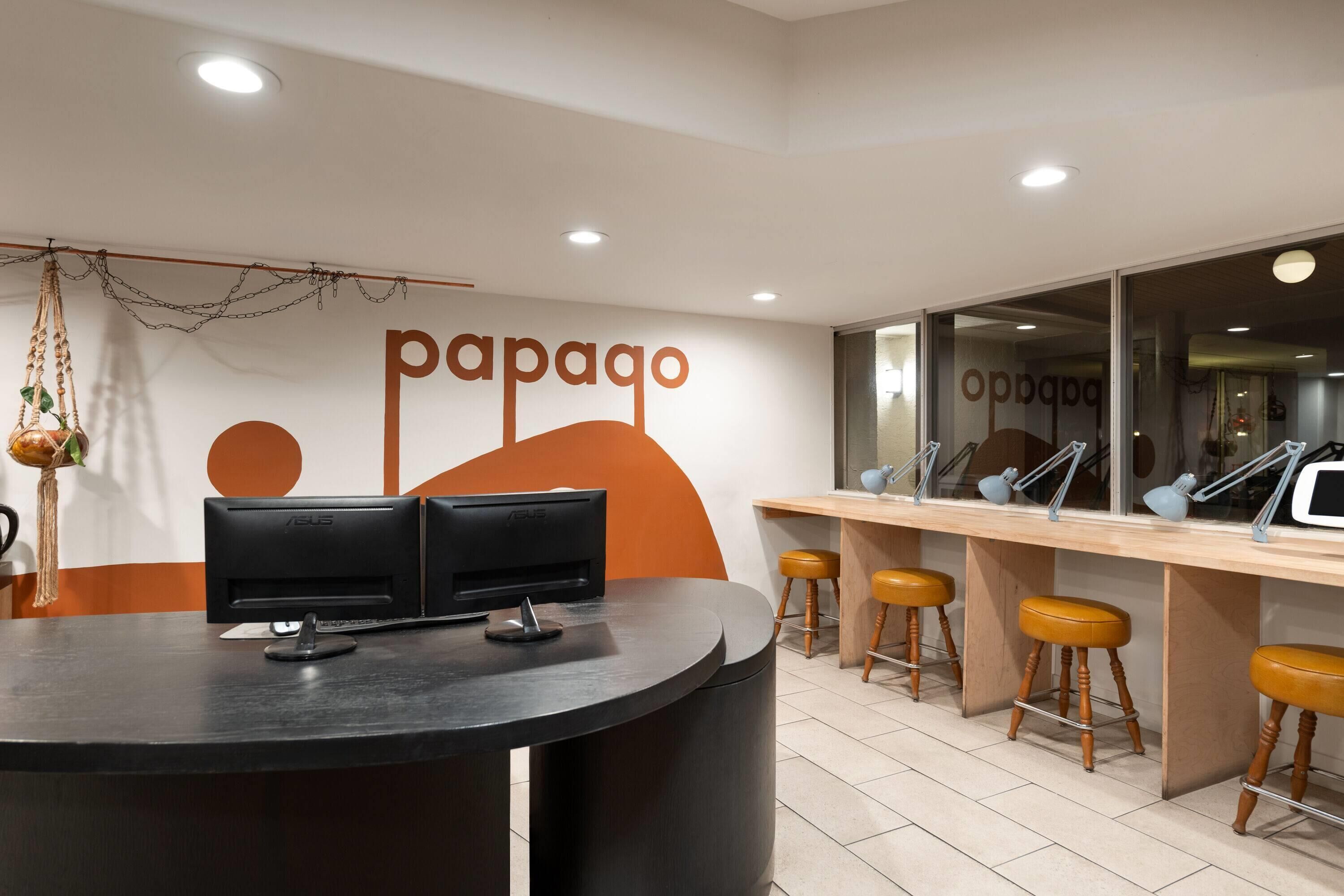 A reception area with a counter, two monitors, and three stools.