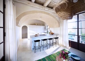 Una cocina moderna con una isla, taburetes de bar y vistas al exterior.