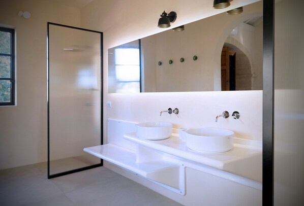 A modern bathroom with two white sinks, a large mirror, and a glass shower enclosure.