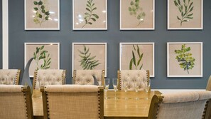 A dining area with six chairs and a table, each with a framed botanical print on the wall behind.