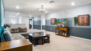 A spacious living room with a sectional sofa, a coffee table, and a TV on a wooden console.