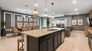 Una cocina moderna con una isla grande, iluminación colgante y un comedor con vistas.