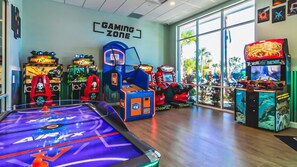 A gaming zone with various arcade machines, a pool table, and large windows offering a view of palm trees. - 8BR @ Windsor Island/Star Wars Gameroom/Themed BR (Davenport)