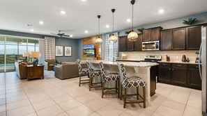A modern kitchen with dark cabinets, a large island with bar stools, a microwave, stove, and a large window overlooking a scenic view. - 8BR @ Windsor Island/Star Wars Gameroom/Themed BR (Davenport)