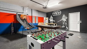 Une pièce équipée d’un baby-foot, d’un panier de basket et décorée avec des œuvres d’art sur le thème de Star Wars.