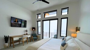 Una habitación de hotel moderna con una cama grande, un escritorio y un balcón con vistas.
