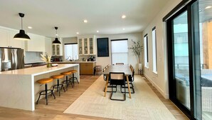 Una cocina moderna con una isla central, taburetes de bar y una mesa de comedor con sillas.
