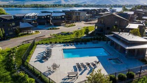 Un resort con varias construcciones, una piscina y vistas a montañas y un lago.
