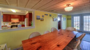 Un coin repas avec une table en bois et des chaises en osier, une cuisine avec des meubles en bois et un ventilateur de plafond.