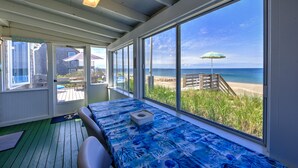 Een kamer met een bed, grote ramen, uitzicht op het strand en een terras aan de buitenkant.