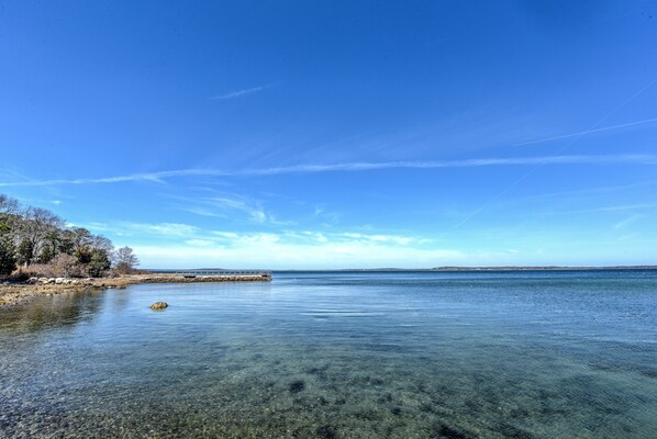 A clear view of a calm lake with a pier extending into the water, surrounded by trees and a clear sky.