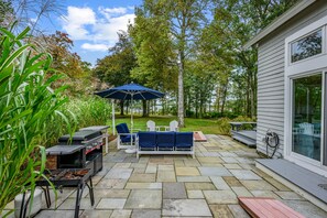 An outdoor patio with a grill, seating, and a view of a lake. - Sun & Serenity at A Wave From It All (Pocasset)