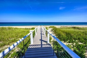A wooden boardwalk leading to a beach with a clear blue sky.