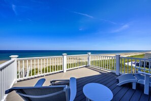 Une terrasse en bois avec des rampes blanches donnant sur une plage.