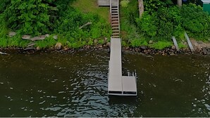 A house surrounded by dense greenery, connected to a dock extending into a body of water. - Lakefront Deck w/ Unmatched View and Location - New Deck (Garrison)