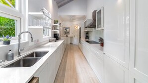 Una cocina moderna con armarios blancos, electrodomésticos de acero inoxidable y suelo de madera.