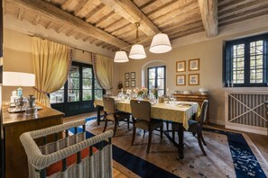 A dining area with a wooden ceiling, a table set for four, and a view of the outdoors.