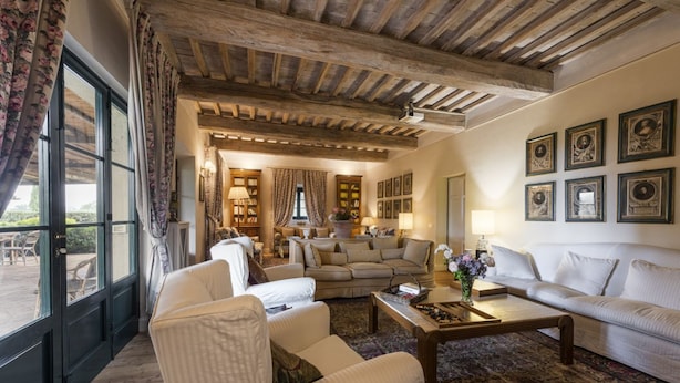 Un accogliente soggiorno con soffitto in legno, un divano, un tavolino da caffè e vista attraverso un'ampia finestra.