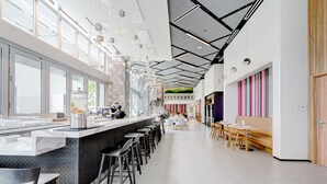 A modern bar area with a long counter, bar stools, and a seating area with tables and chairs.