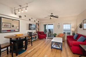 A spacious living room with a dining area, a red sofa, and a ceiling fan.
