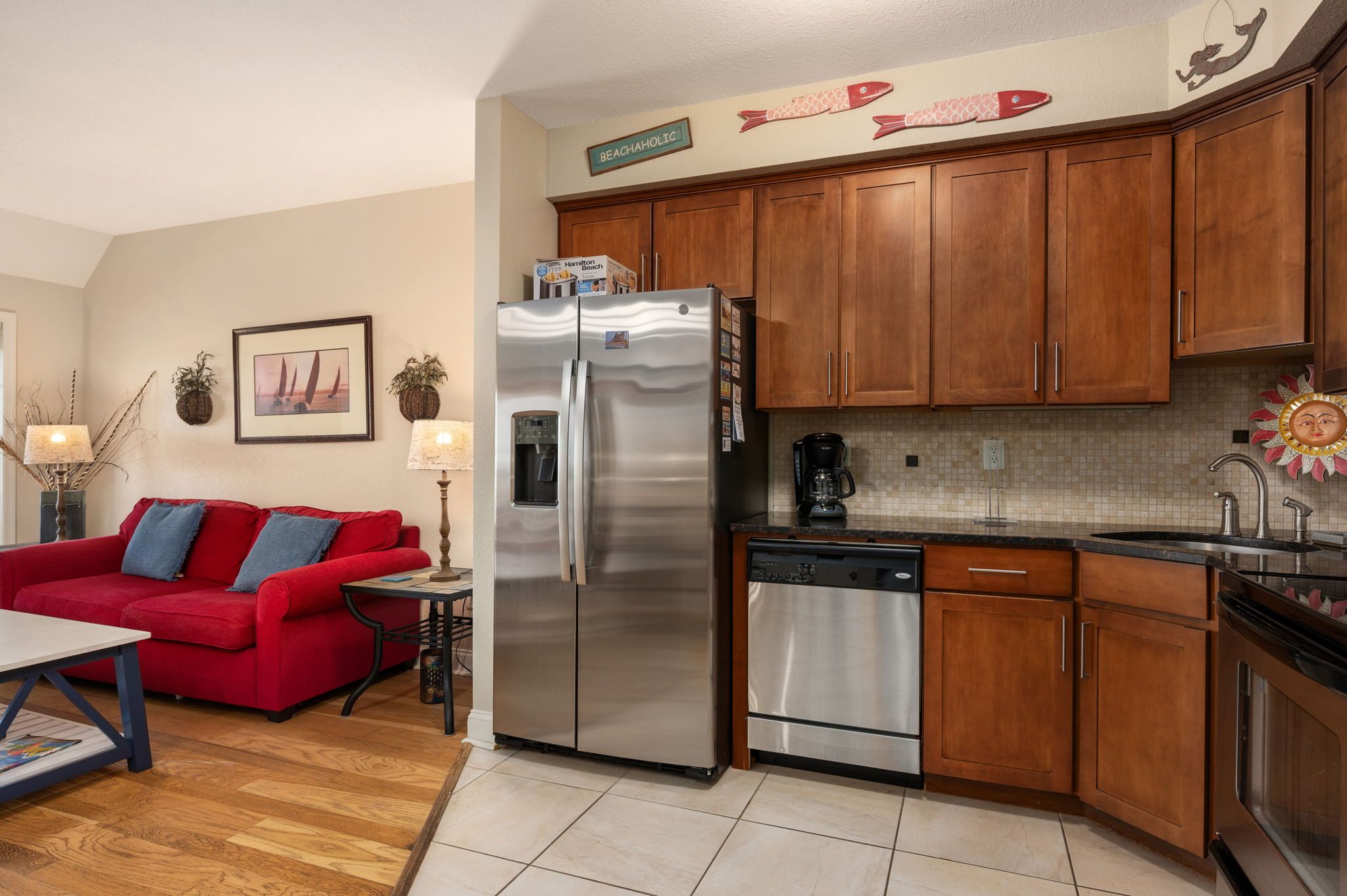 A compact kitchen with wooden cabinets, a stainless steel refrigerator, and a dishwasher.