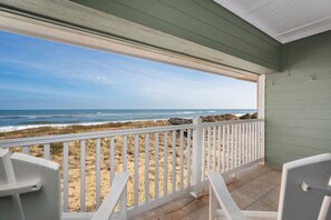 A balcony with a view of the beach and ocean.