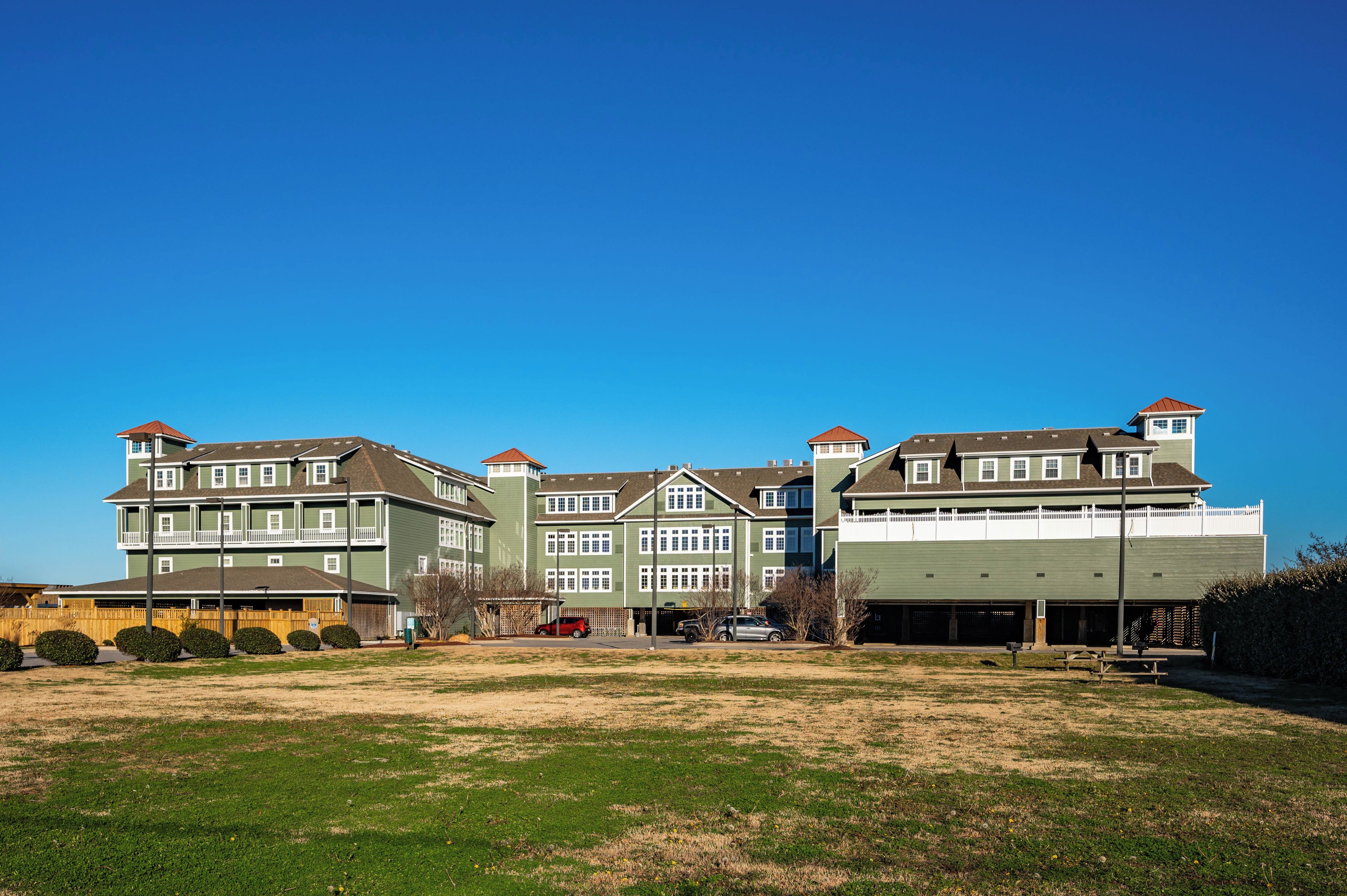 A large, multi-story residential building with a green exterior and multiple windows.