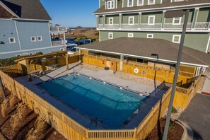 A rectangular swimming pool with a wooden deck and a lifeguard stand.