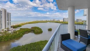 Ein Balkon mit Korbmöbeln mit Blick auf einen Fluss und eine Stadtansicht.