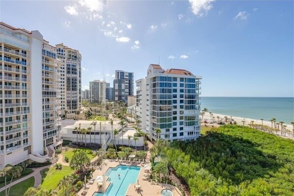 Un hotel de gran altura con varios balcones, una zona de piscina y vistas a la playa.