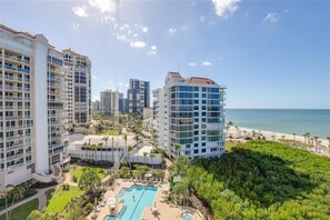 A high-rise hotel with multiple balconies, a pool area, and a beach view.