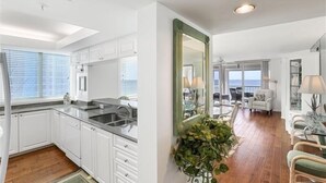 Una cocina moderna con armarios blancos, encimera negra y un ventanal grande.