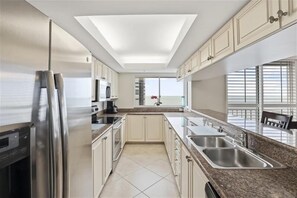 A modern kitchen with a skylight, stainless steel appliances, and a large window providing a view. - Enjoy life in this 3 bedroom beachfront condo-CL1201 (Naples)