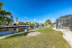 Een pand aan het water met een gazon, een kleine vijver en een modern gebouw met een overdekt terras.