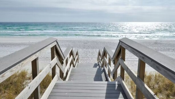 Een houten looppad naar een strand met uitzicht op de oceaan.