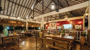 Un restaurante espacioso con mesas y bancos de madera, un techo alto con vigas a la vista y una pared de acento roja.