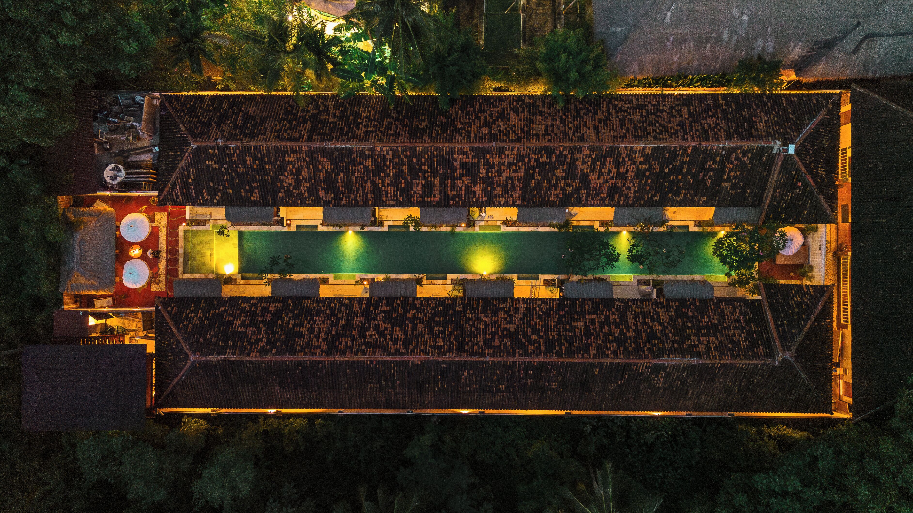 Une vue aérienne d’un bâtiment rectangulaire doté d’une piscine centrale, entourée d’une zone abritée avec des sièges.