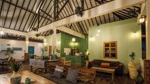 Amplio espacio interior con mobiliario de madera, un mostrador de recepción y paredes verdes.