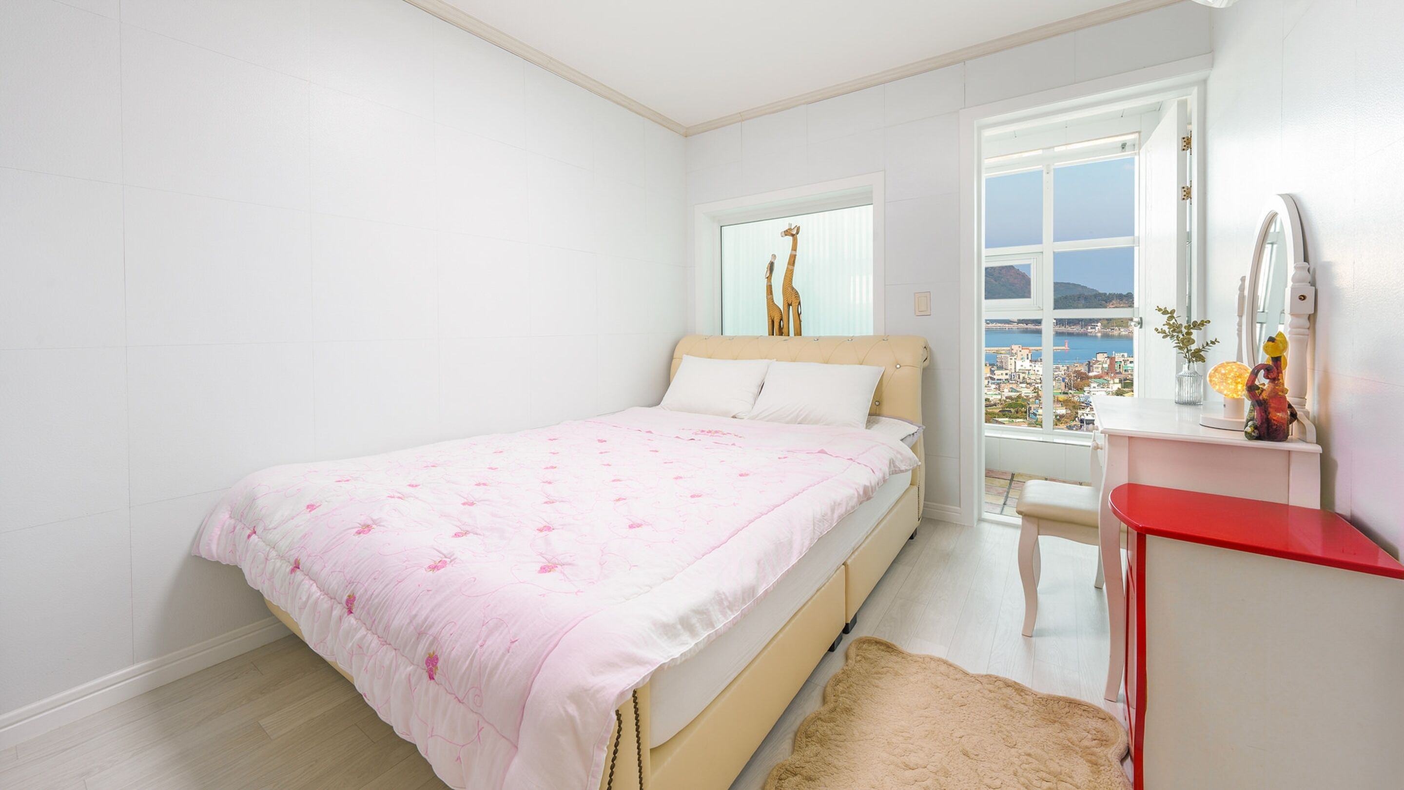 A bedroom with a bed, a window with a view, a dresser, and a chair.