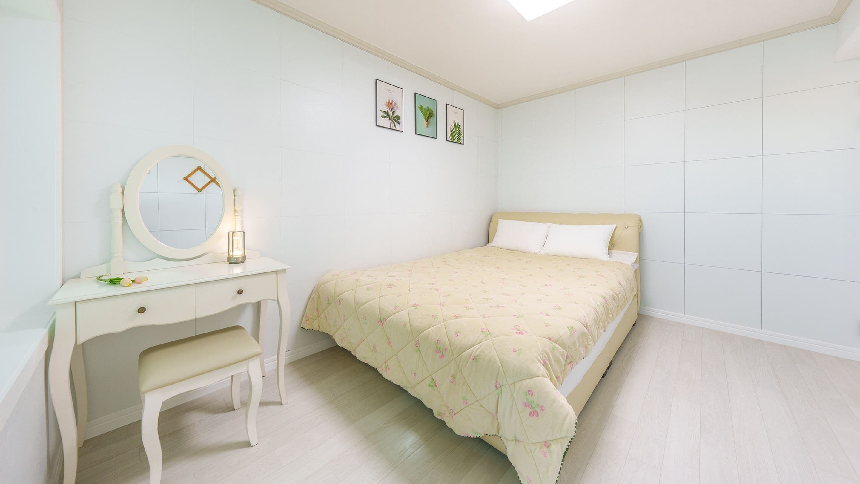 Un dormitorio con cama, mesita de noche con espejo y cómoda.