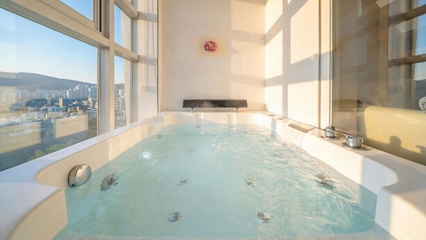 Un amplio jacuzzi interior con vistas a la ciudad, un banco y función de vapor.