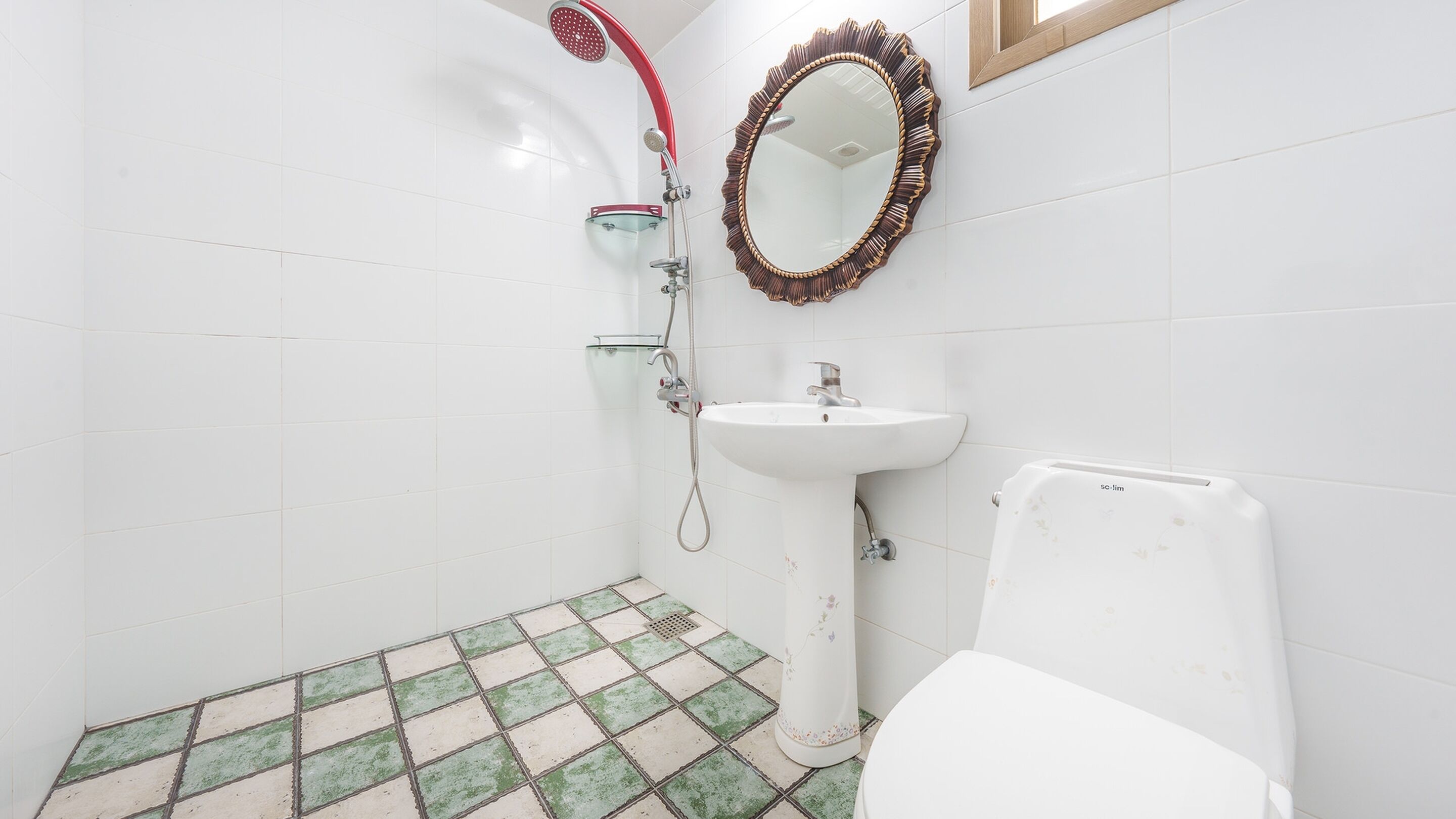 Un baño con azulejos blancos, ducha, lavamanos e inodoro.
