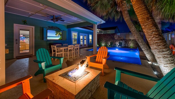 Zona junto a la piscina con una chimenea, asientos exteriores y vista al agua.