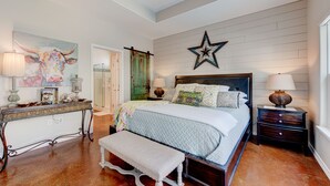 Un dormitorio con cama, mesitas de noche, un banco, cómoda y una decoración con forma de estrella.