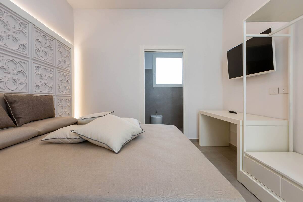 Une chambre à coucher moderne avec un lit, des oreillers, une télévision et une armoire intégrée.