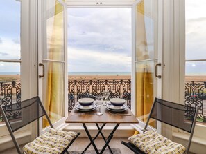 A balcony with a table set for two, overlooking a beach. - The Old Spy Headquarters (Folkestone)