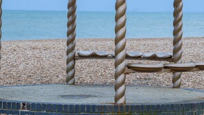 A beach with a metal spiral structure, pebbles, and the sea in the background. - The Old Spy Headquarters (Folkestone)