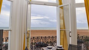 An open balcony with a table set for dining, overlooking a beach with a cloudy sky. - The Old Spy Headquarters (Folkestone)